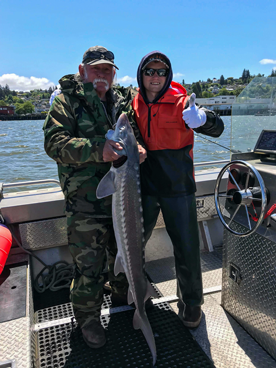 Brian Liebert Poses with a Guest and His Sturgeon